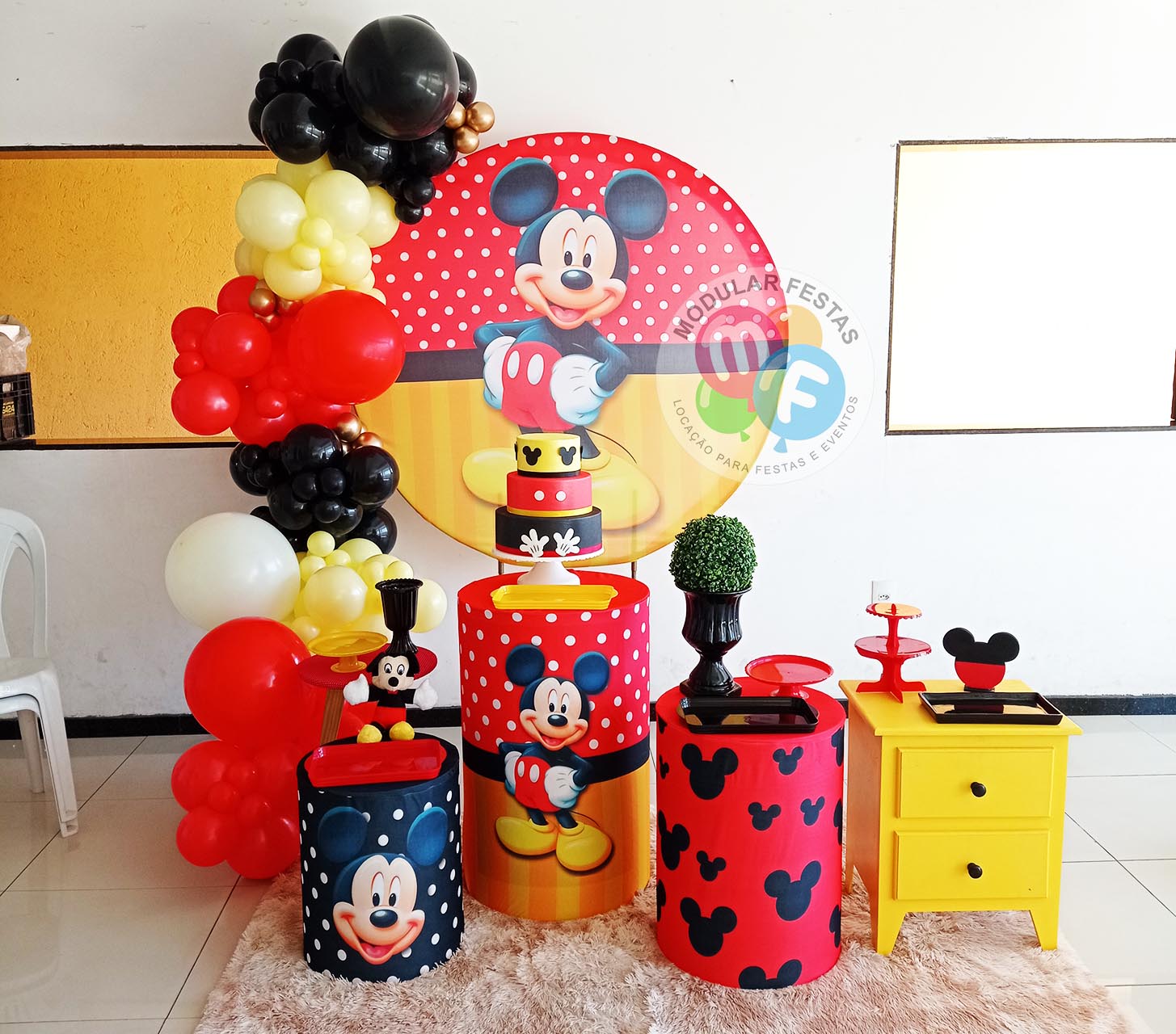 Kit Pegue e Monte infantil e juvenil festa de aniversário temática Mickey Mouse Disney preto e vermelho com trio cilindros de MDF e painel de aro redondo com capas personalizadas e cômoda amarela.